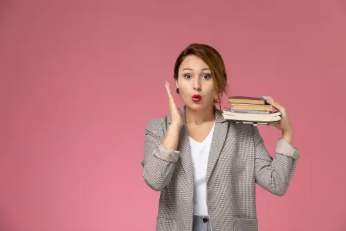 Jovem aluna com casaco cinza posando segurando livros com expressao de surpresa